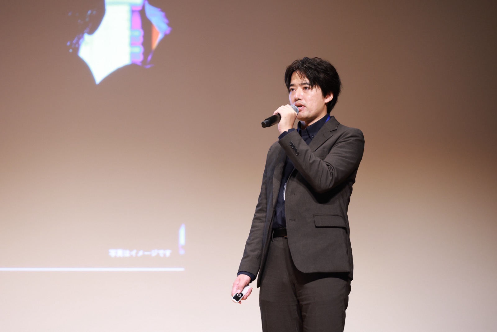 TOCHIGI STAR☆TO UP NIGHT 2026 のステージで、スライドを背にマイクを持って話す代表の黒田